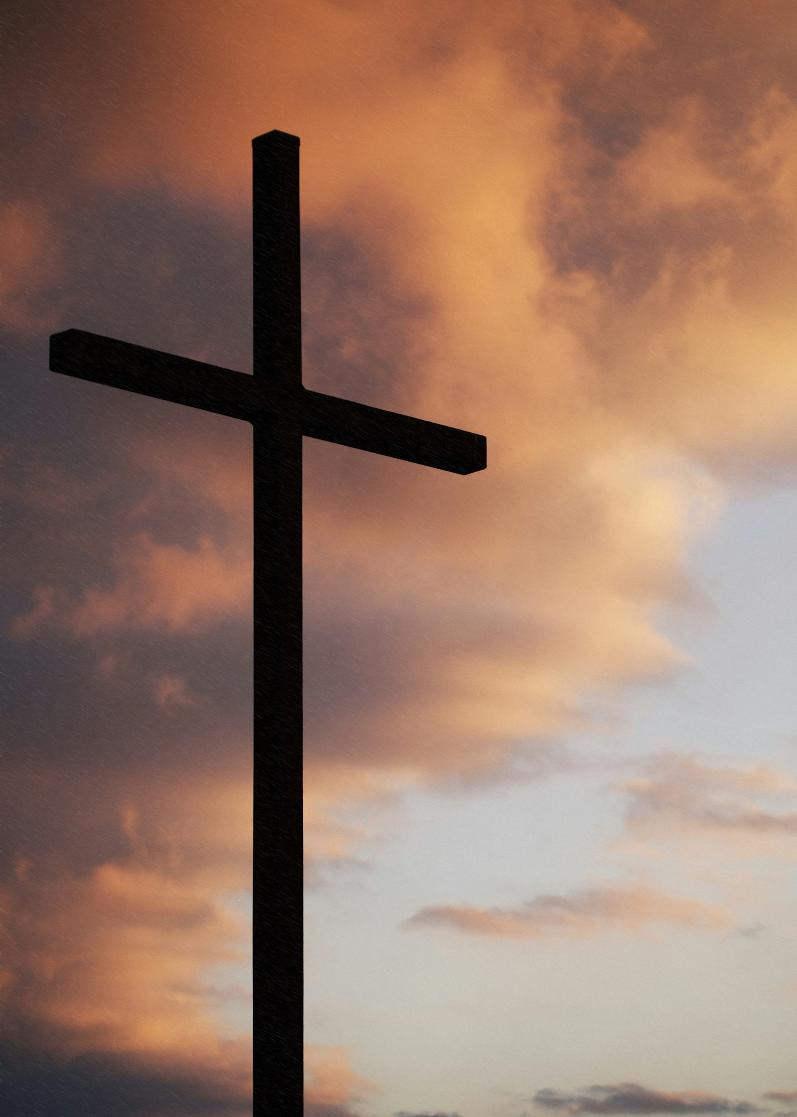 A silhouette of a cross against a glowing sunset sky